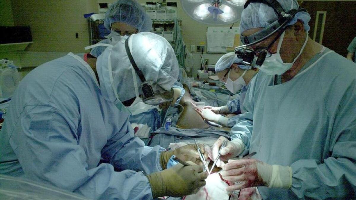 
Dr. John Sutton, assisted by surgical technician Mike Jacobs, performs a multiple heart bypass surgery at Providence Hospital.
