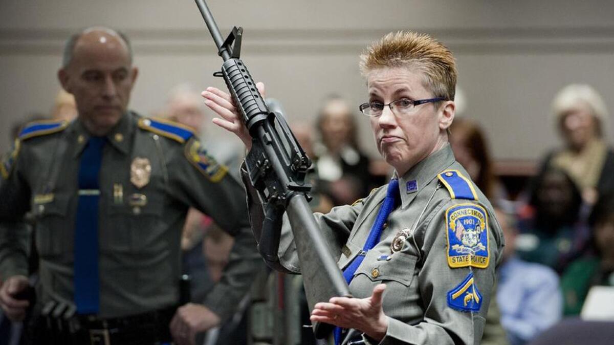 A Connecticut State Police firearms training officer holds up a Bushmaster AR-15 rifle for a demonstration during a legislative hearing.