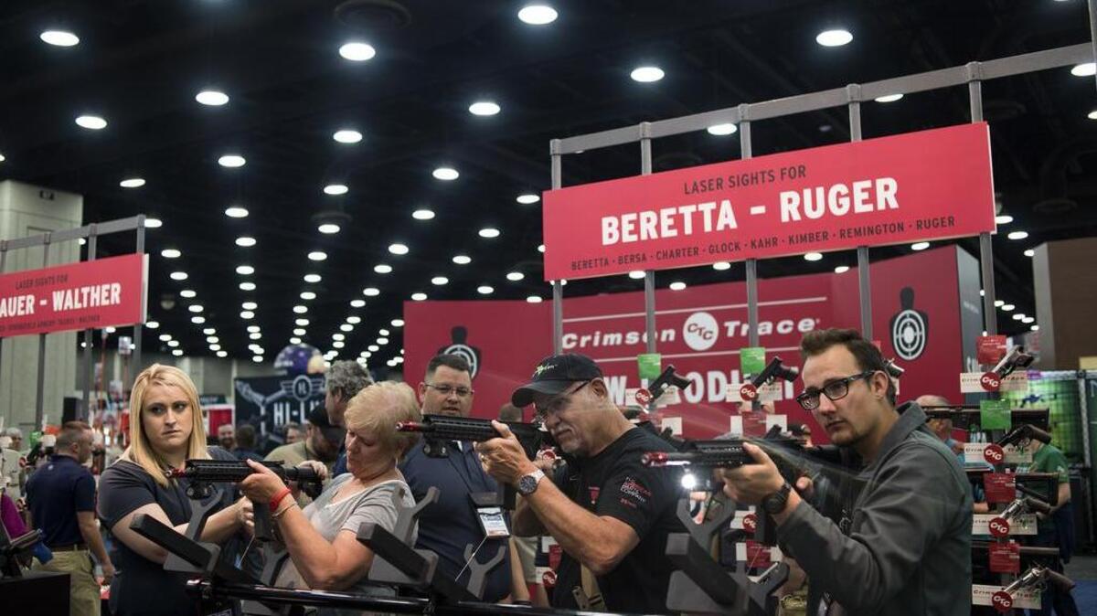 People shoot firearms at a screen during the a National Rifle Association convention in 2016.