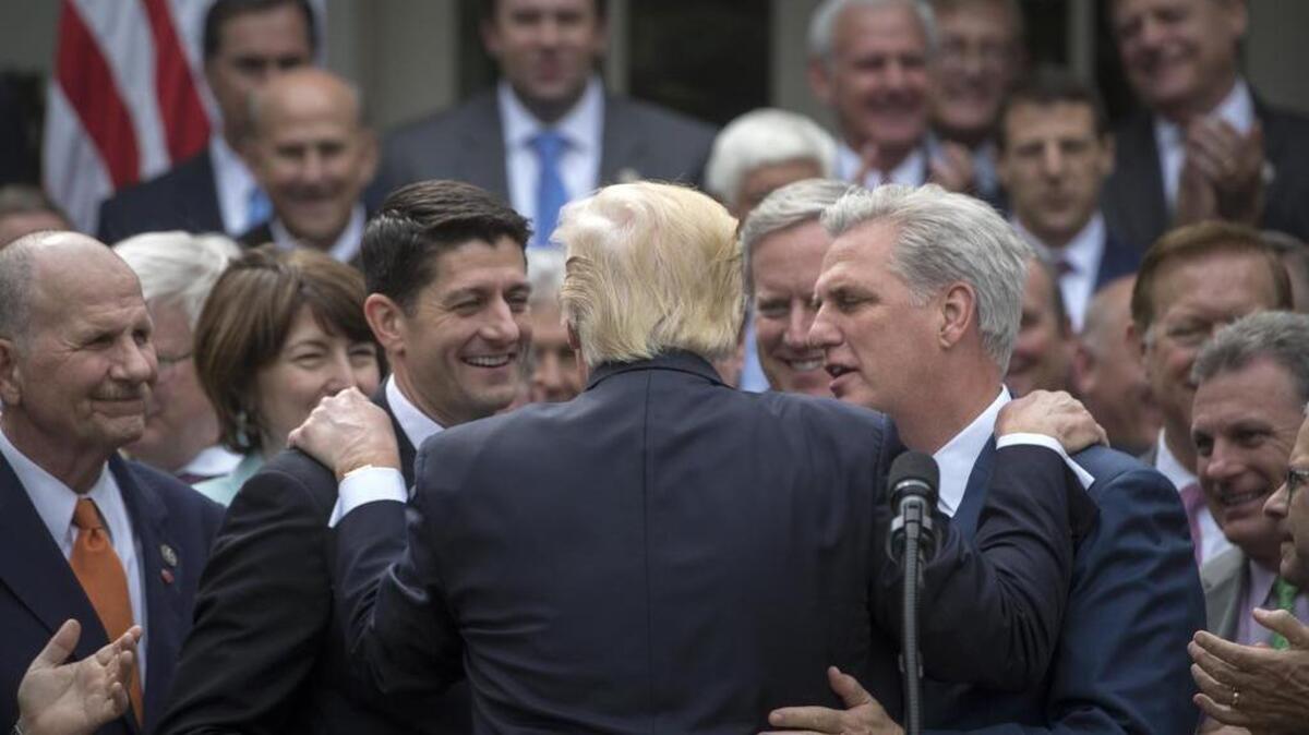 President Donald Trump embraces House Speaker Paul Ryan and House Majority Leader Kevin McCarthy.