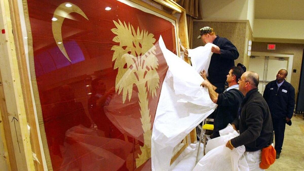
Workers at the Citadel remove the protective covering from "Big Red" at the Citadel Alumni Center. The flag is believed to be the one that flew over Morris Island when Citadel cadets fired upon the supply ship The Star of the West.
