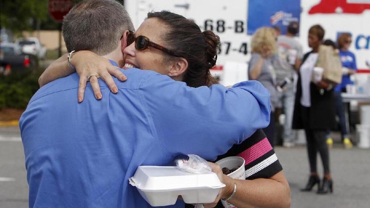 
Angela Riggs of Forest Acres hugs First Citizens Bank employee Terrance Schafer after the bank and Bill Ellis Barbeque provided free lunches Friday at Trenholm Plaza, in the heart of some of the worst flood destruction.
