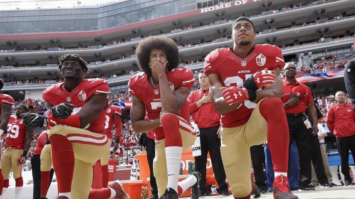 In this Oct. 2, 2016, file photo, from left, San Francisco 49ers outside linebacker Eli Harold, quarterback Colin Kaepernick and safety Eric Reid kneel during the national anthem before an NFL football game against the Dallas Cowboys in Santa Clara, Calif.