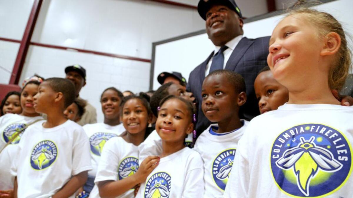 Columbia Mayor Steve Benjamin is surrounded by children from the Boys & Girls Club of The Midlands as they unveil the new logo of the Columbia Fireflies.