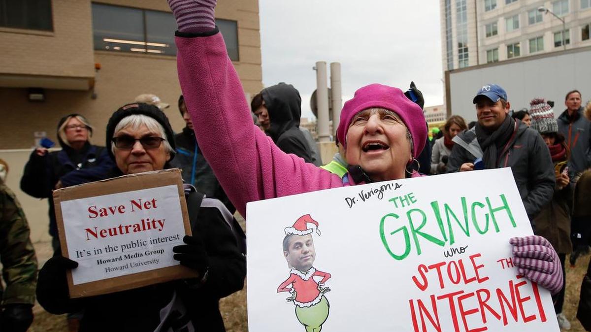 Diane Tepfer holds a sign with an image of Federal Communications Commission Chairman Ajit Pai as the “Grinch who Stole the Internet” after the FCC voted to eliminate net-neutrality protections for the internet.