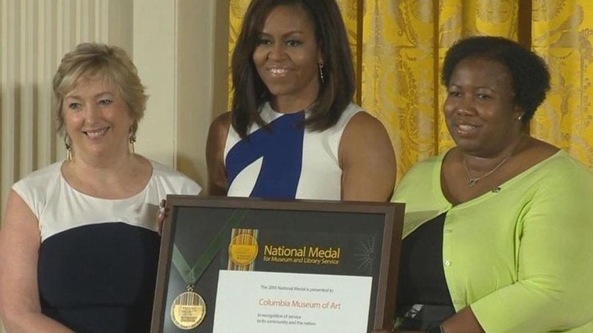 First lady Michelle Obama presents Karen Brosius, left, and Joyce Rose-Harris with a 2016 National Medal for Museum and Library Service award.