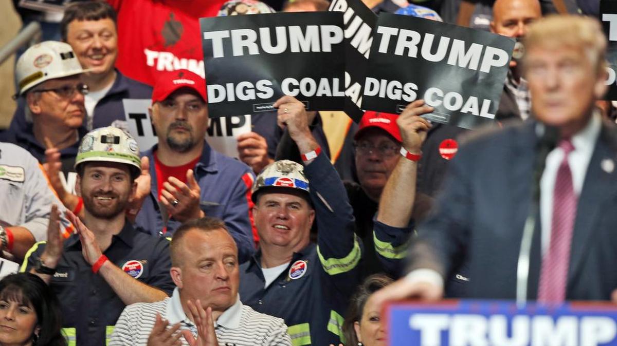 In this 2016 photo, coal miners wave signs as Republican presidential candidate Donald Trump speaks during a rally in Charleston, W.Va.