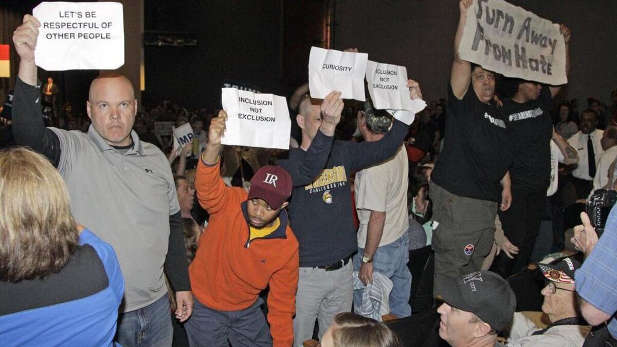 Protesters hold up signs at a Donald Trump rally Monday at Lenoir-Rhyne University in Hickory, NC.