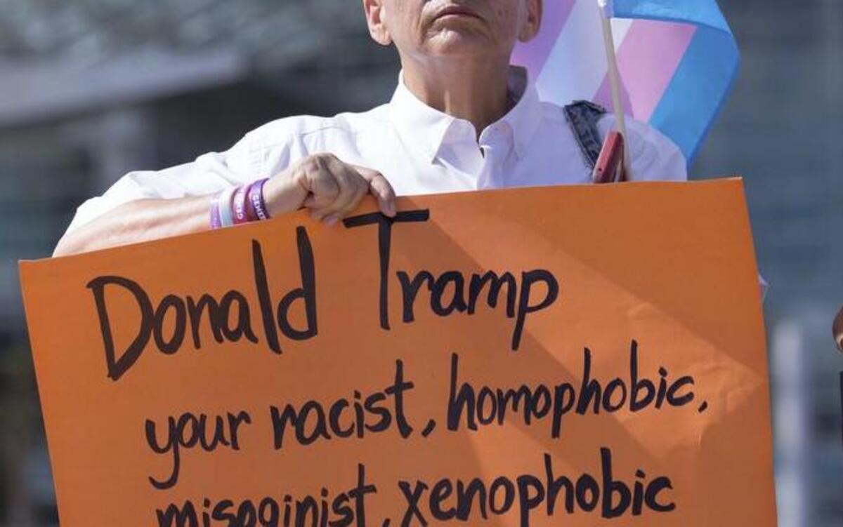 Trans activist Kery John Santiago holds up a sign denouncing President Donald Trump’s visit to Puerto Rico Tuesday.