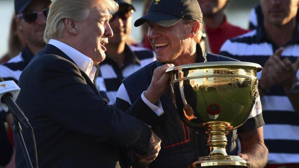President Donald Trump presents the winner’s trophy to U.S. Team Captain Steve Stricker after the final round of the Presidents Cup golf tournament on Sunday.