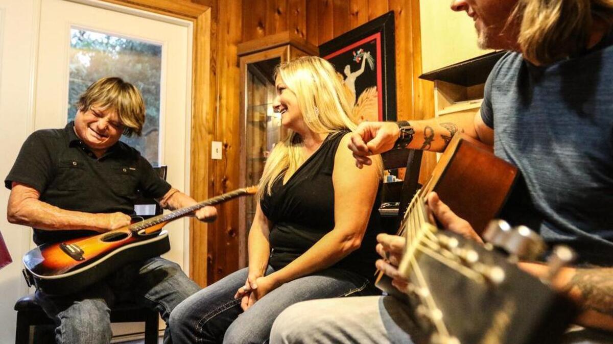 Joe Bates plays guitar while his wife, Erin, sings at their home in Lexington.