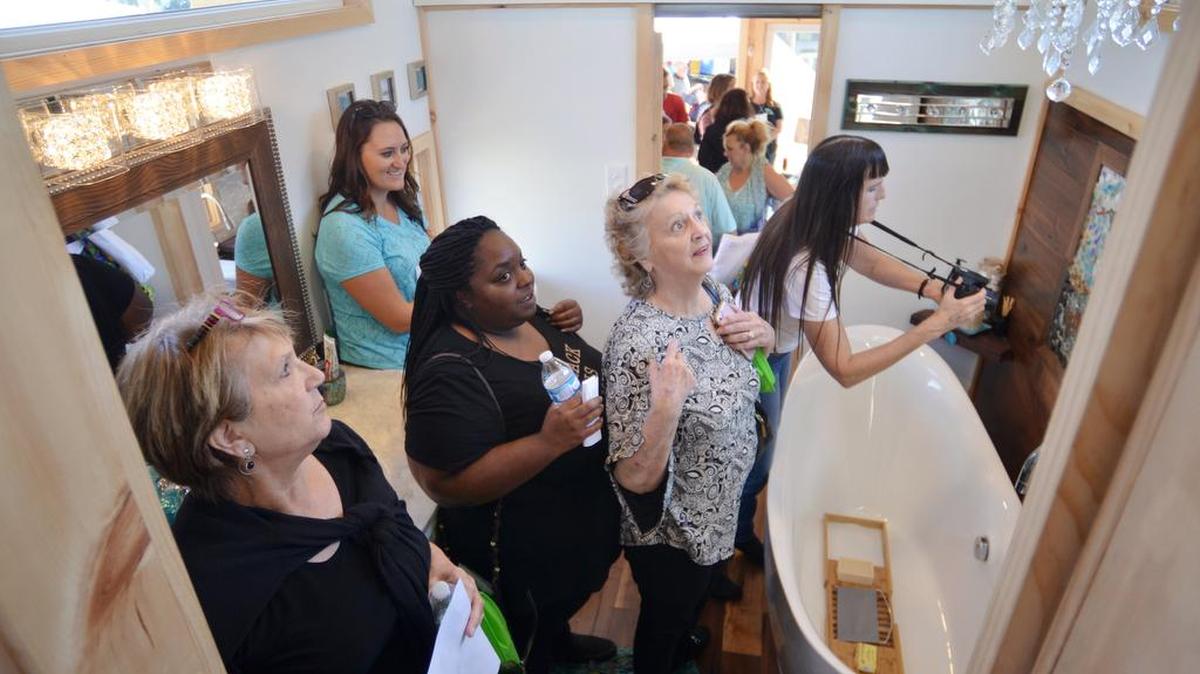 Attendees marvel at the bathroom of a 40-foot-long, 306-square-foot home at the Tiny Home Show in Hilton Head. The bathroom includes an 8-foot soaking tub, handelier, mural and combination washer and dryer.