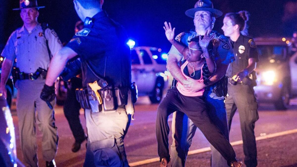 A police officer carries a young woman down the road where Huger Street turns into Interstate 126 during a July 10 march.