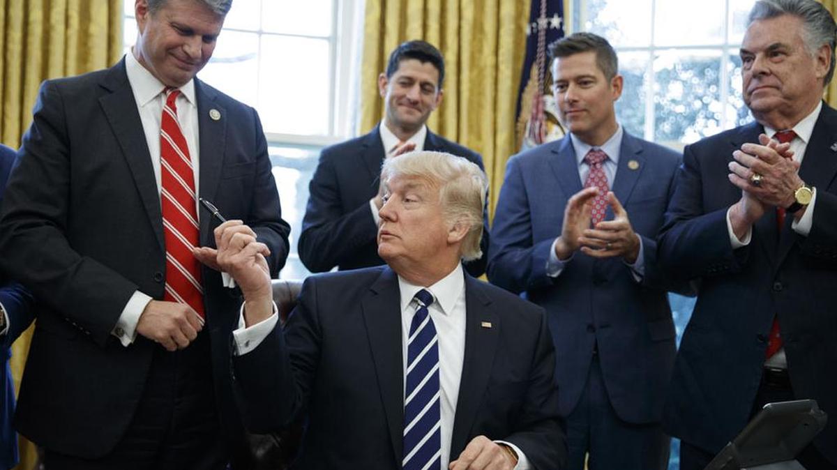 President Donald Trump hands a pen to Rep. Bill Huizenga, R-Mich., after signing a join resolution in February. From left are, Huizenga, Trump, House Speaker Paul Ryan of Wis., Rep. Sean Duffy, R-Wis., and Rep. Peter King, R-N.Y.