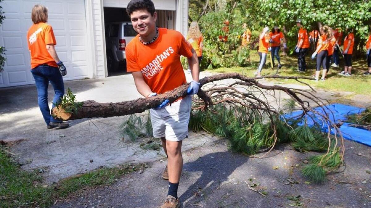 Micah Burton totes a tree branch out a storm-ravaged Bluffton yard on Wednesday a he volunteers with the international Christian relief organization Samaritan’s Purse.