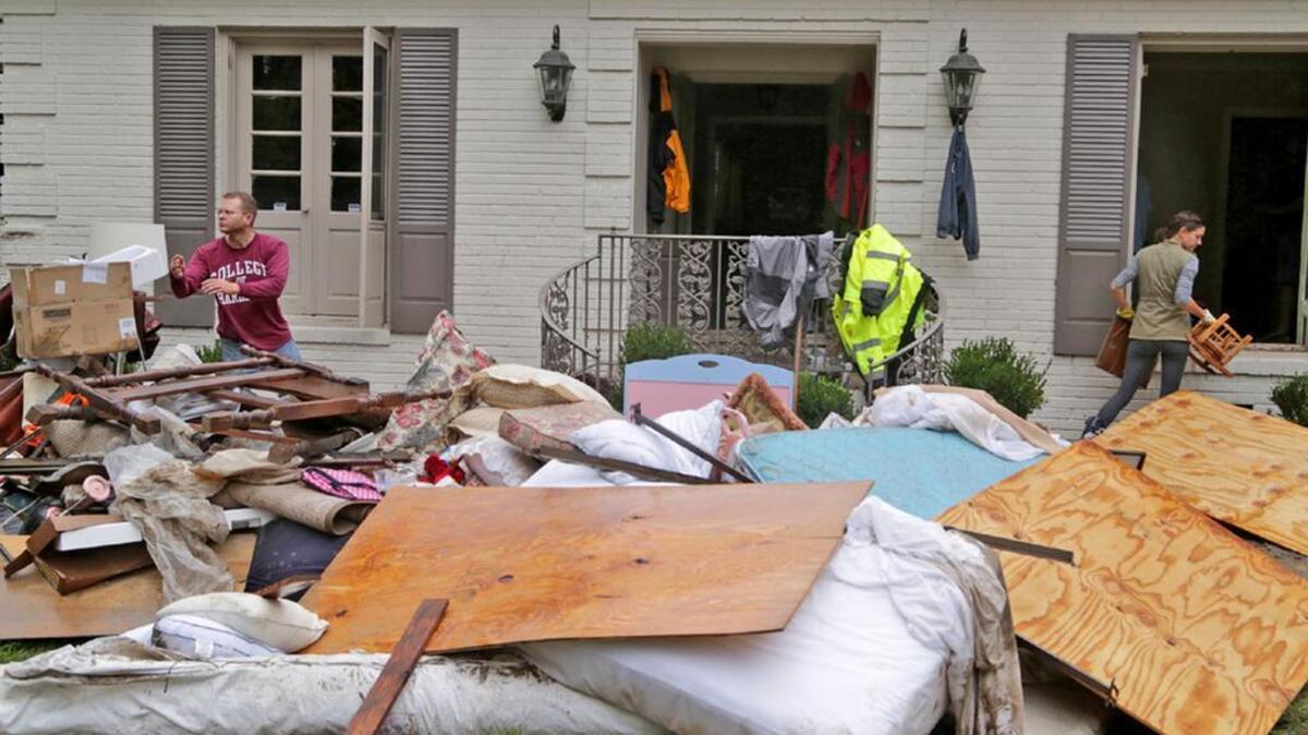 Alex McLaughlin, and Marianna Cartin go through water-damaged items from Marianna and Walt Cartin’s home after the October floods.