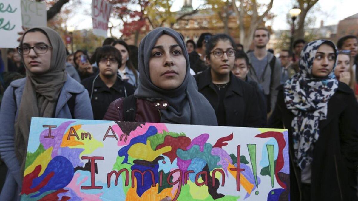 A Rutgers student holds a sign as she joins a large crowd gathered to protest some of President-elect Donald Trump policies . College students at campuses across the country held rallies and walkouts Wednesday to call on school administrators to protect students and employees against immigration proceedings under the Trump administration.