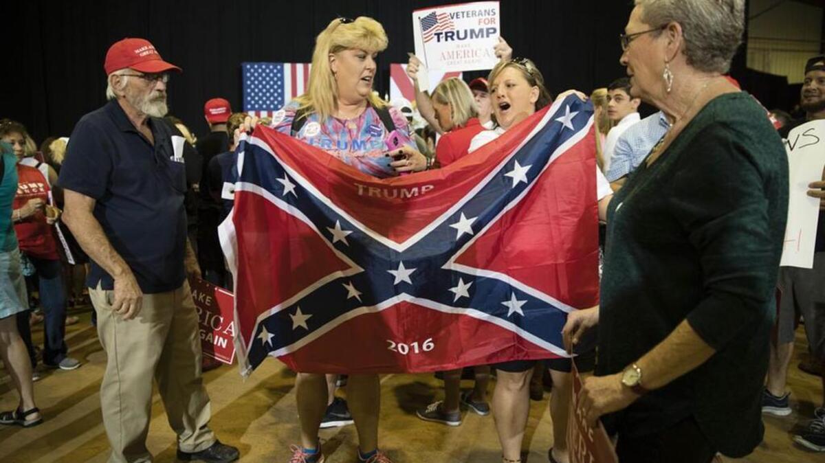 Robin Sirois and Tina Edwards pose for photographs with a Confederate flag ahead of a Republican presidential candidate Donald Trump campaign stop in Jacksonville, Fla., the week before the electoin.