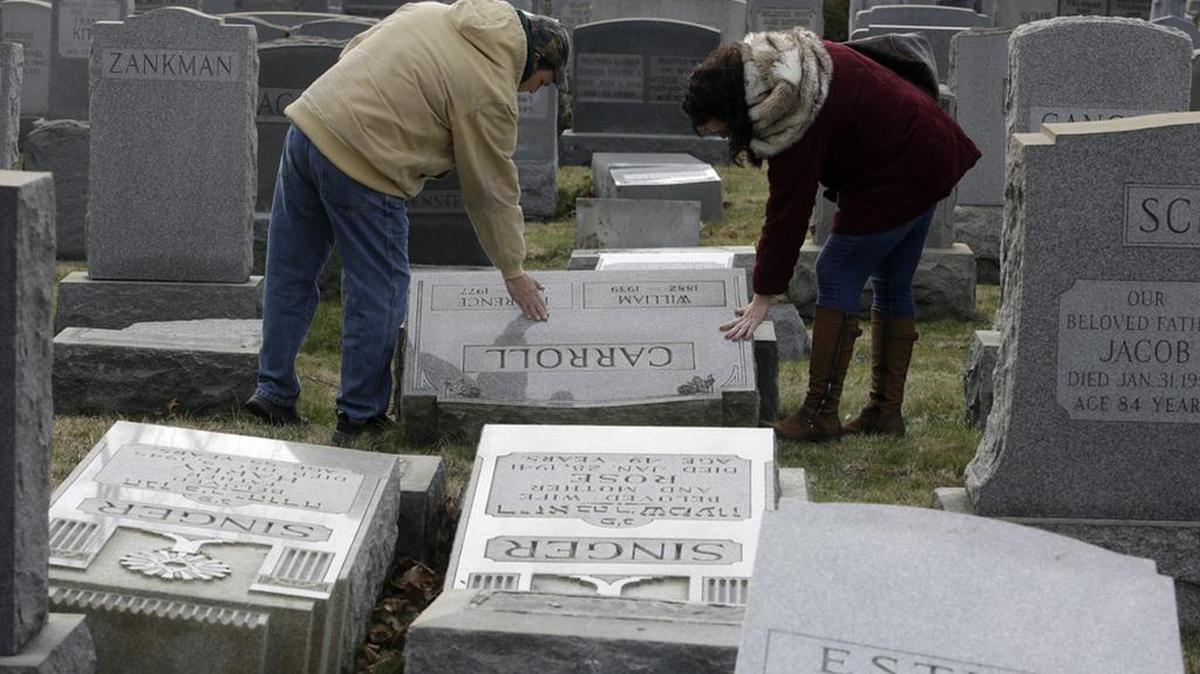 Joe Nicoletti and Ronni Newton pay their respects at a damaged headstone in Mount Carmel cemetery in Philadelphia. More than 100 headstones were found vandalized last week, less than a week after similar vandalism in Missouri, authorities said.(AP Photo/Jacqueline Larma)