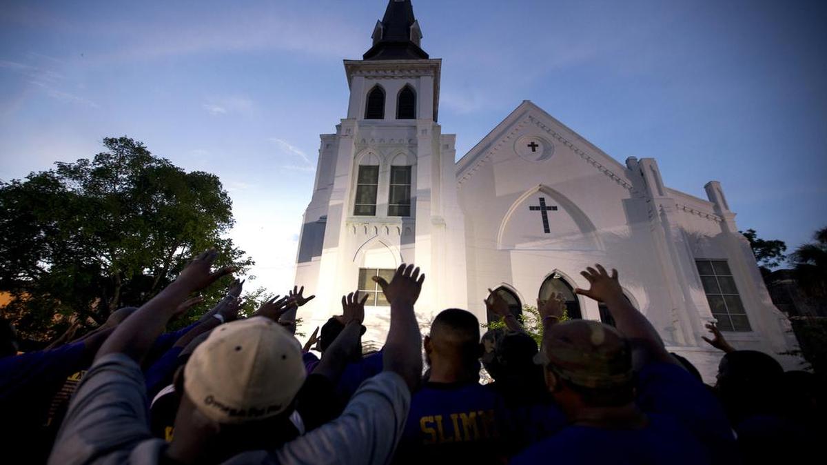 The men of Omega Psi Phi Fraternity lead a crowd of people in prayer outside the Emanuel AME Church on June 19, 2015, two days after nine people were shot to death inside.