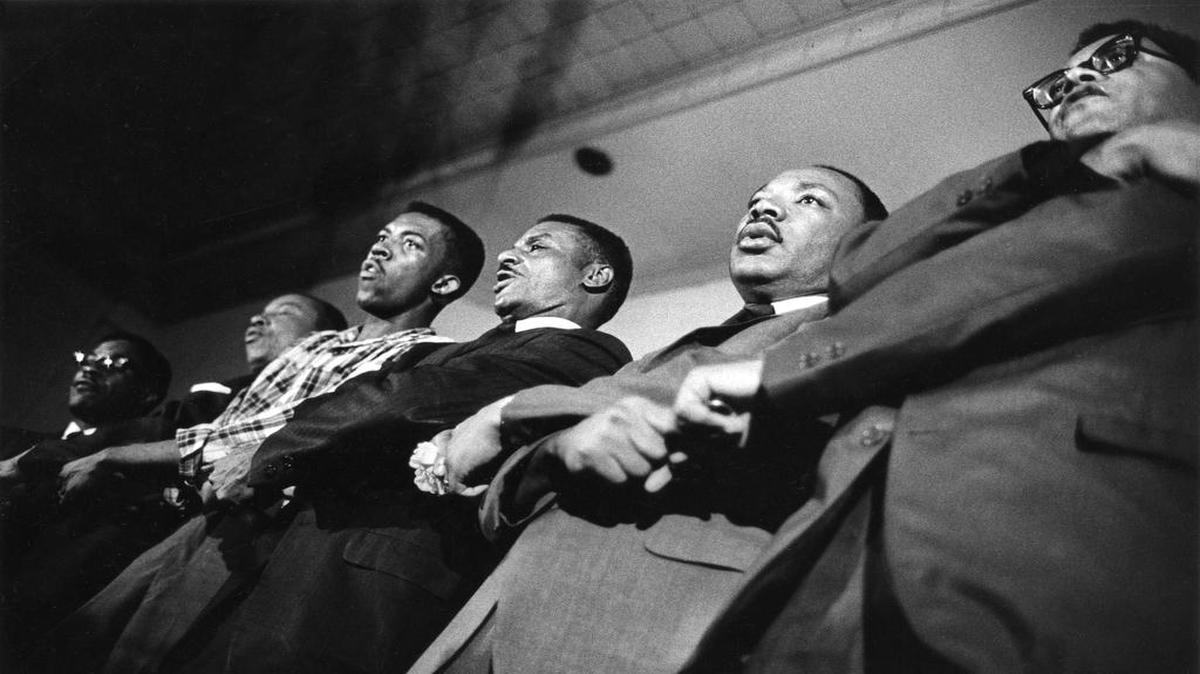 The Rev. Fred Shuttlesworth, Martin Luther King Jr., and the Rev. James Lawson singing “We Shall Overcome” at a Southern Christian Leadership Conference staff workshop at Penn Center on St. Helena Island in 1966.
