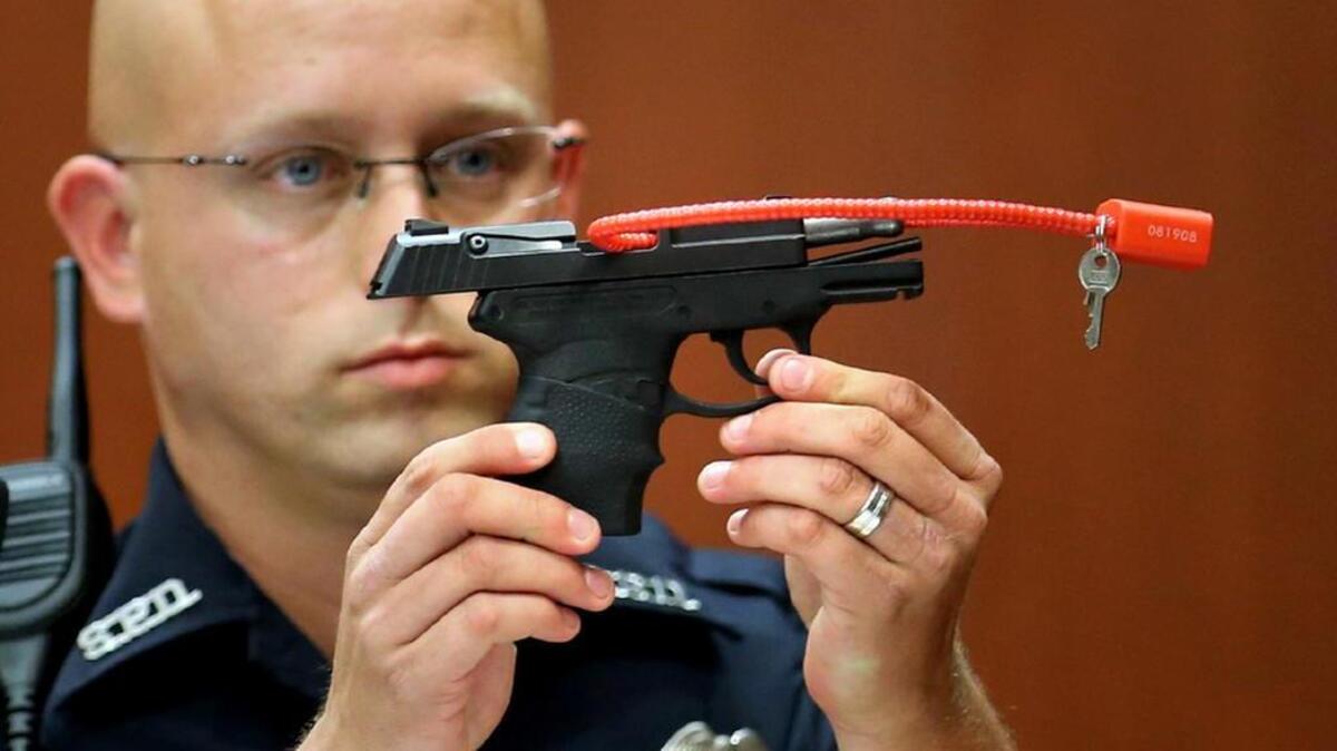 In this 2013 photo, Sanford police officer Timothy Smith holds up the gun that was used to kill Trayvon Martin, while testifying in the George Zimmerman trial. Zimmerman put the pistol up for auction last week.