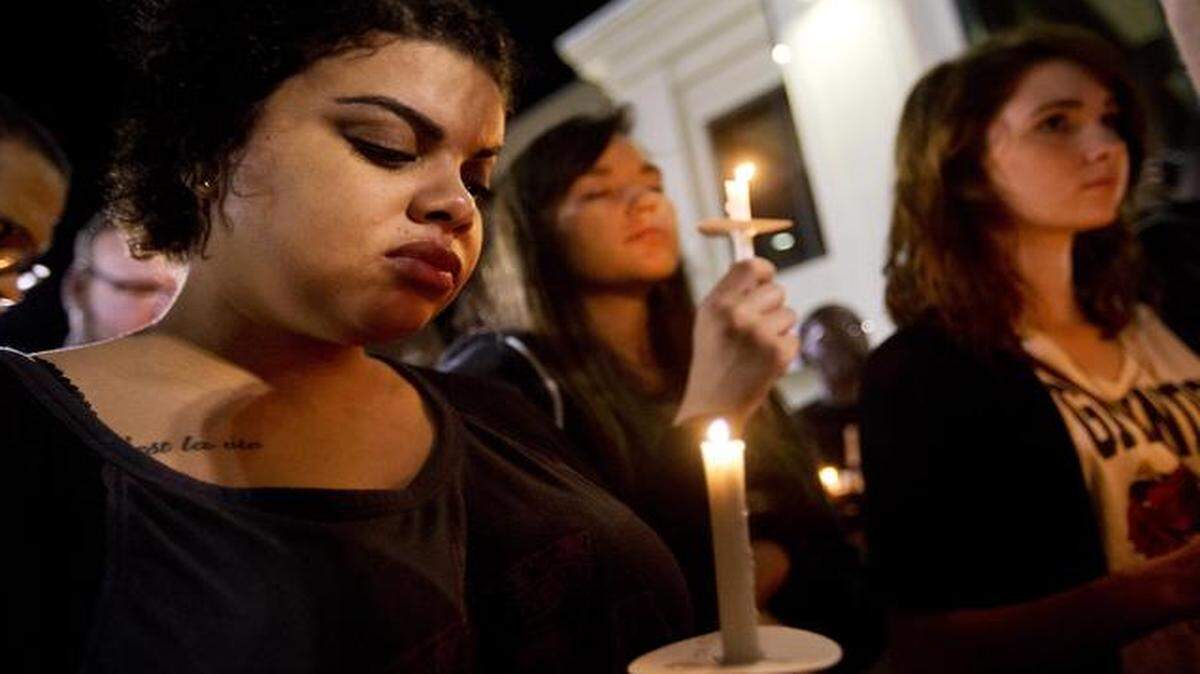 
Jasmine Huber, left, observes a moment of silence during a candlelight vigil Wednesday outside the North Charleston City Hall to protest the shooting death of Walter Scott by a North Charleston police office after a traffic stop.
