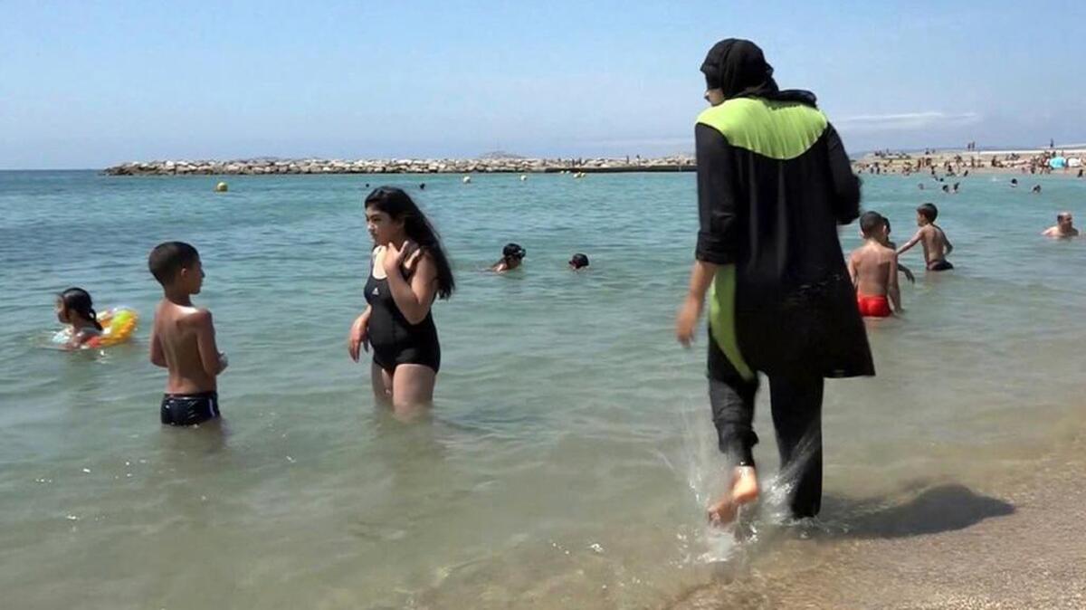 Nissrine Samali, 20, gets into the sea earlier this month wearing a burkini, a wetsuit-like garment that also covers the head, in Marseille, southern France. France's Socialist prime minister Manuel Valls is expressing support for local bans of burkinis, saying the swimwear is based on the “enslavement of women” and therefore not compatible with French values.