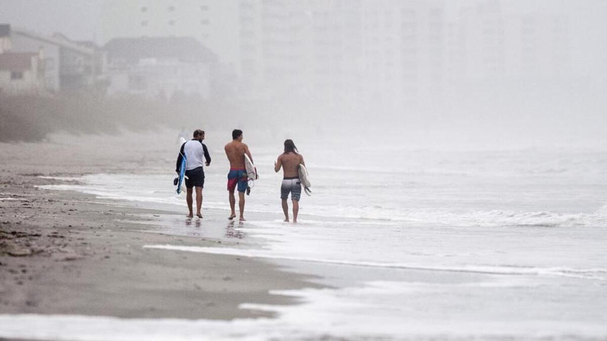 Surfers walk along North Myrtle Beach Friday morning during after taking advantage of large waves pushed ahead of Hurricane Matthew.