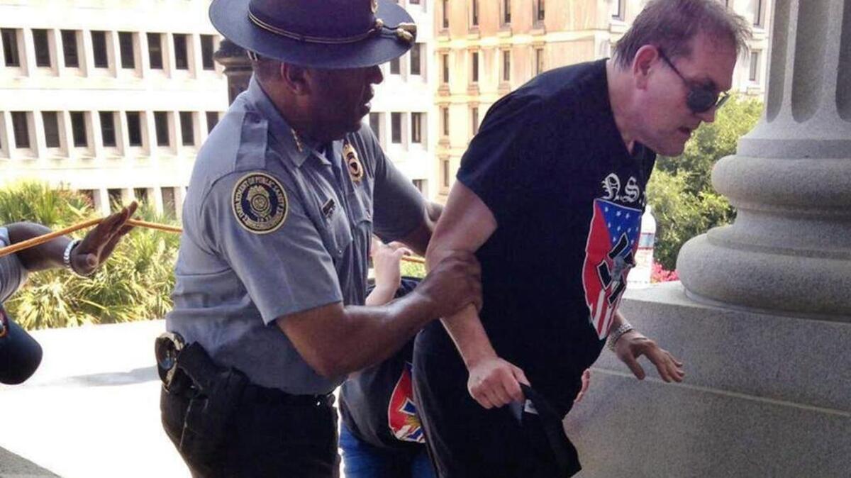 
S.C. Public Safety Director Leroy Smith helps a white supremacist out of the heat at the July 18 KKK rally at the State House.
