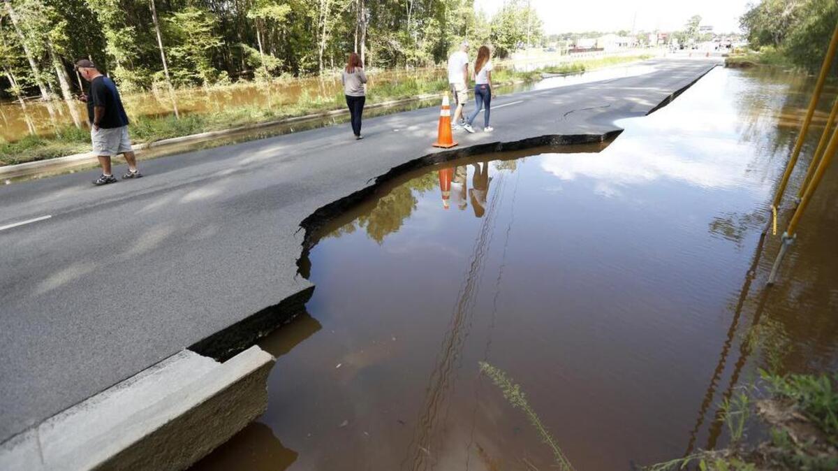 
Pedestrians walk down Dorchester Road as Sawmill Branch Canal near Summerville begins to wash away after the deluge.
