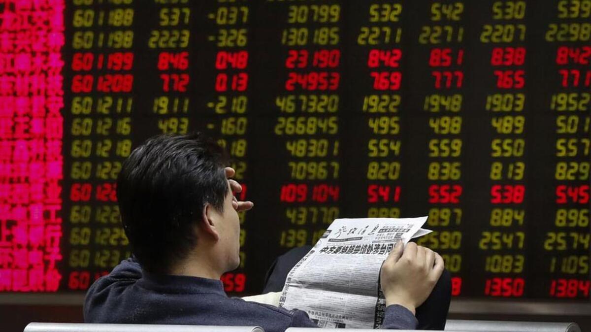 A broker in Beijing reads a newspaper Monday with the headline that reads “China want U.S. President-elect Donald Trump use caution in dealing with Taiwan issue.”