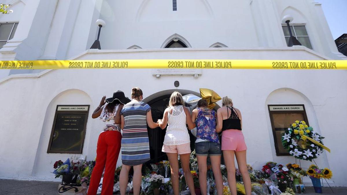 A group of women pray together at a make-shift memorial on the sidewalk in front of the Emanuel AME Church the day after the massacre.