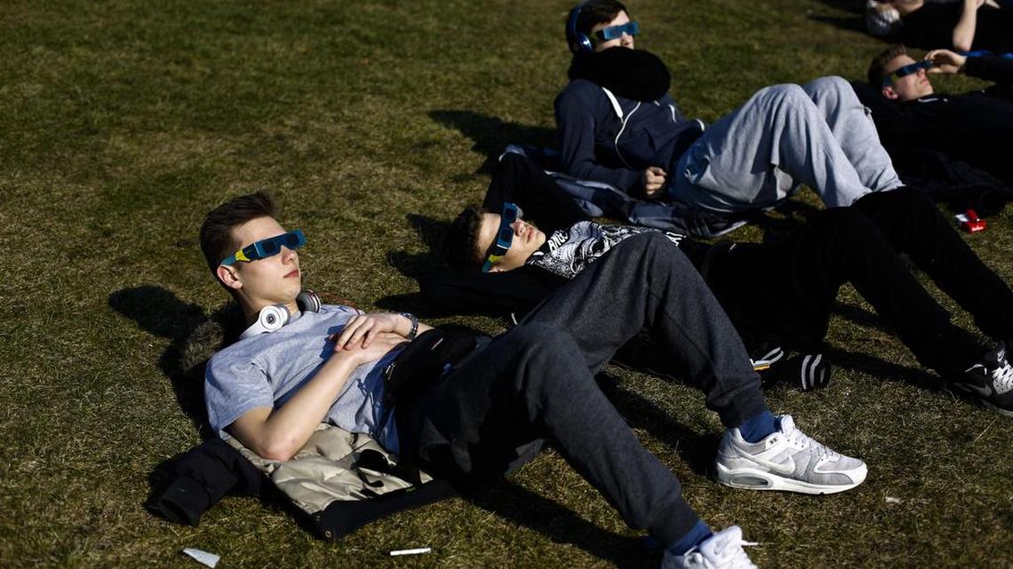 Young men watch a solar eclipse in Berlin in 2015.