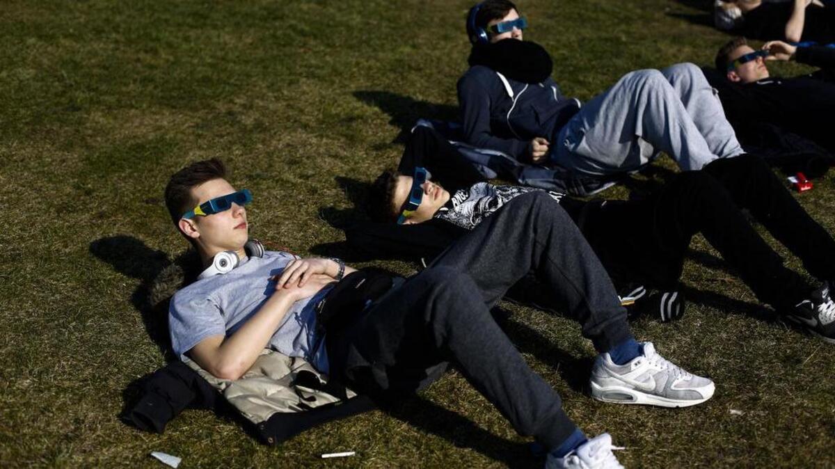 Young men watch a solar eclipse in Berlin in 2015.