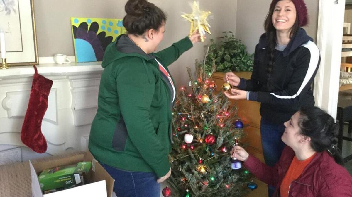 Volunteers Faith Harrington, left, Bekah Crowe, top right, and Alyssa Boss decorate one of the Christmas trees donated at Pilgrims Inn in Rock Hill.