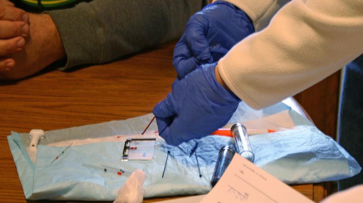A home-health nurse draws blood from a patient for testing.
