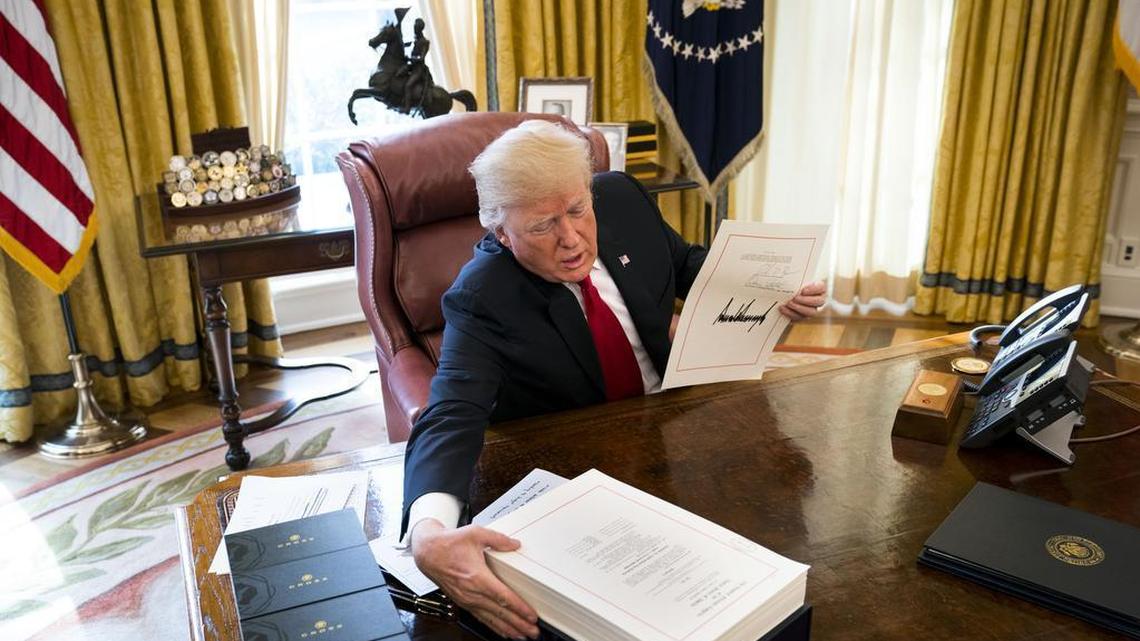 Then-President Donald Trump displays his signature on a sweeping tax cut bill that he signed in 2017.