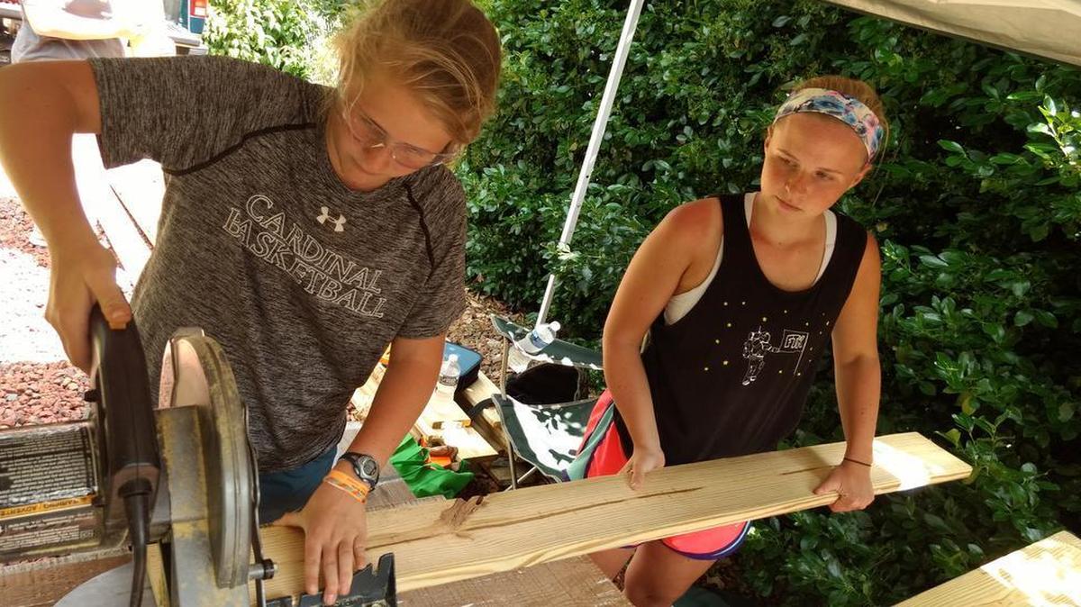 Emily and Morgan Megna saw deck boards for a wheelchair ramp.