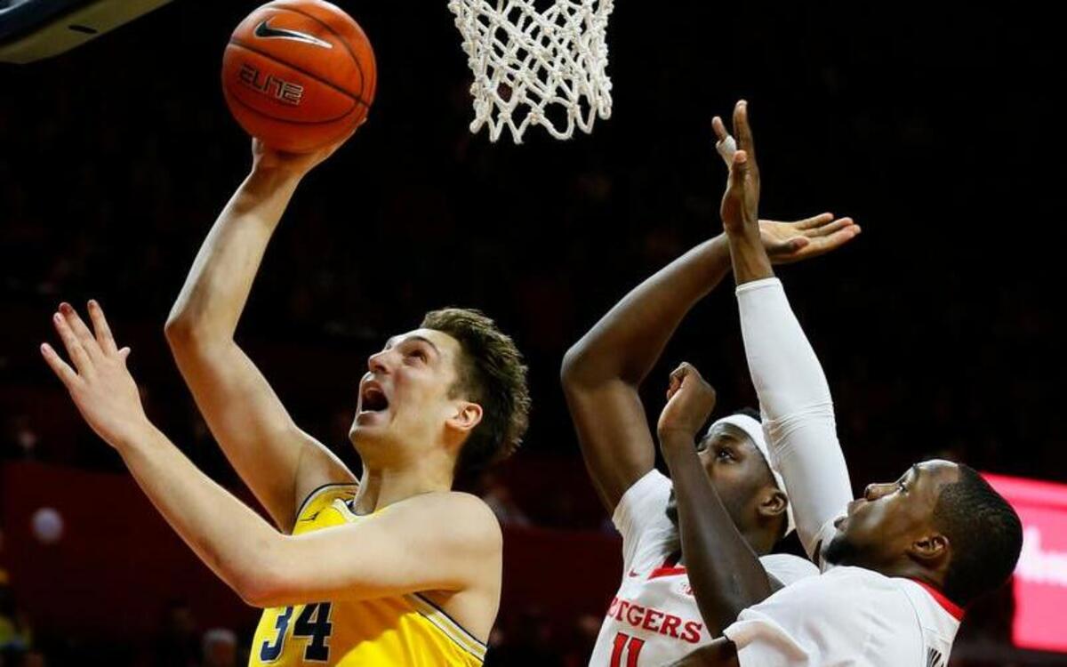 Michigan Wolverines forward Mark Donnal (34) goes to the basket against Rutgers Scarlet Knights forward Eugene Omoruyi (11) and guard Mike Williams (5)