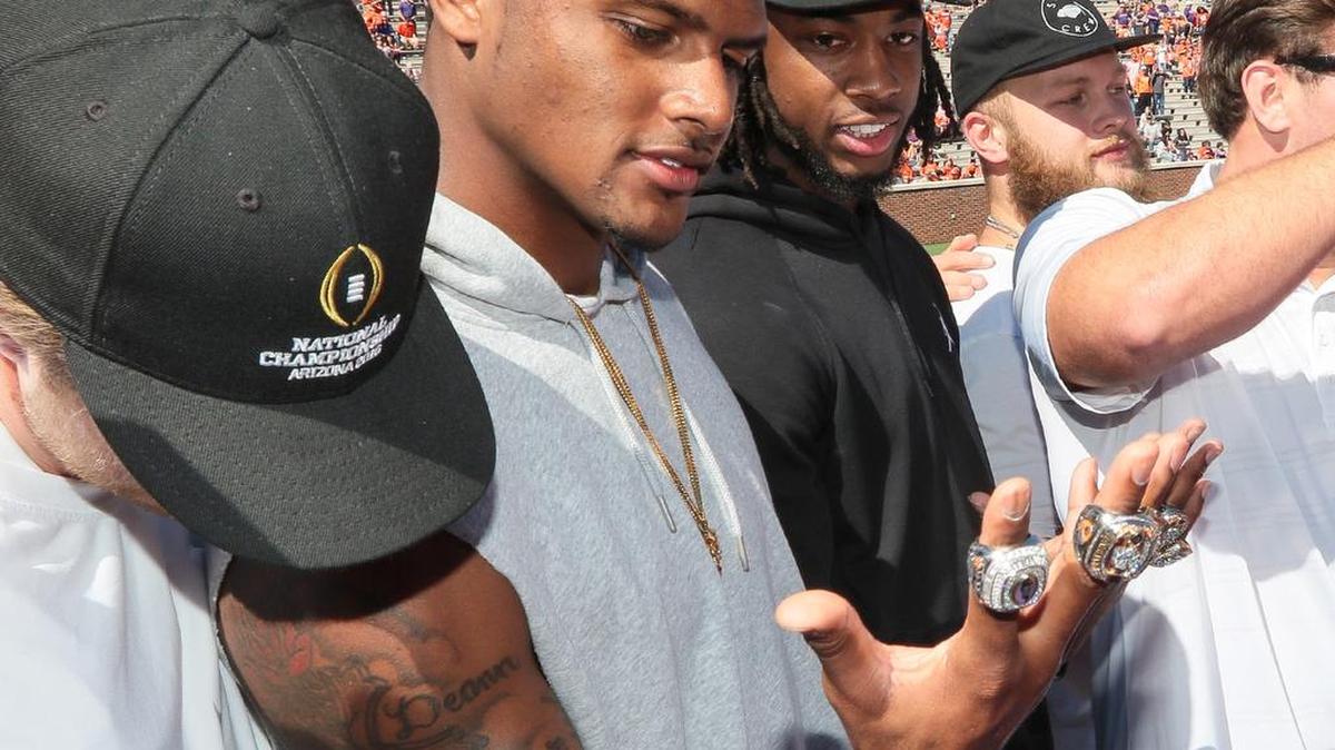 Former Clemson quarterback Deshaun Watson, left, Mike Williams, and Ben Boulware, right, look at championship rings presented to them during halftime of Clemson's NCAA college football spring game at Memorial Stadium in Clemson.