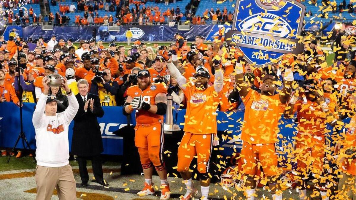 Clemson coach Dabo Swinney, left, holds up the trophy for fans after winning the ACC championship.