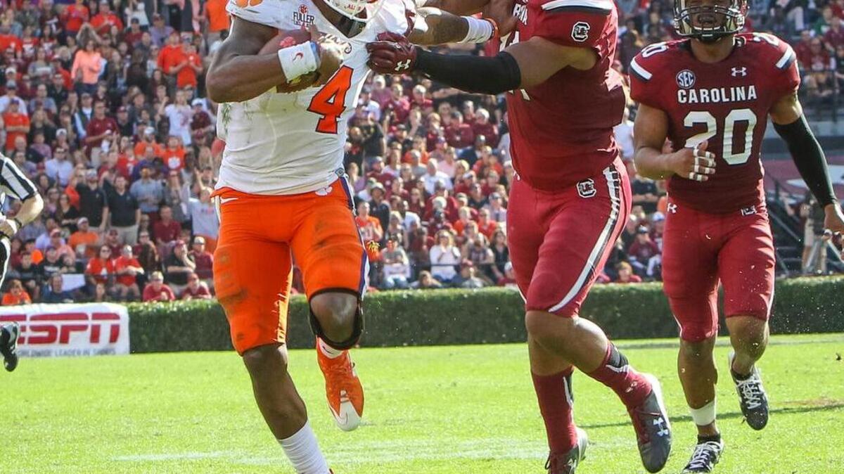 Clemson quarterback Deshaun Watson (4) pushes off South Carolina linebacker T.J. Holloman (11) on his touchdown run during the USC-Clemson game Saturday at Williams-Brice Stadium.