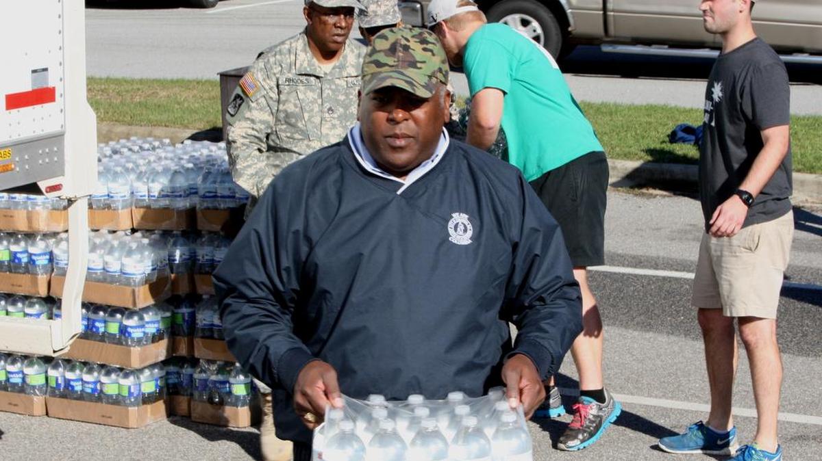 
Volunteers, including Columbia Mayor Steven Benjamin, distribute water this week to people in need at Lower Richland High School. Many roads are out in the area, making it difficult for people to get food and water.
