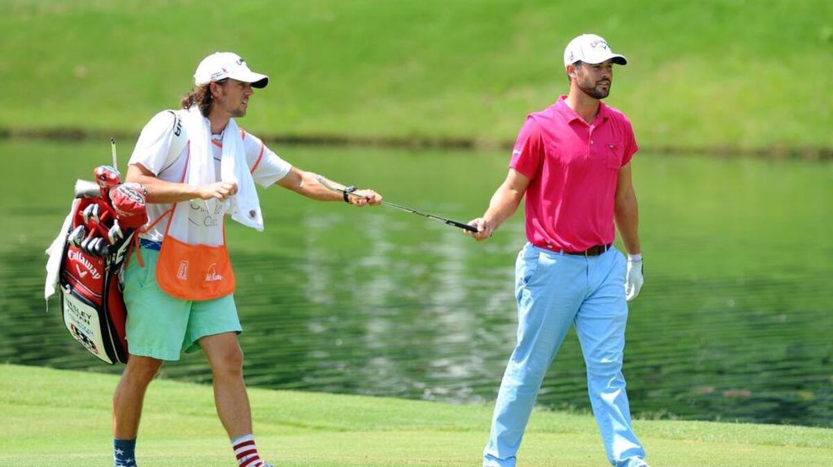 Wesley Bryan (R) hands his club to his brother and caddie George Bryan (L) after his second shot on the 18th hole during the final round of the FedEx St. Jude Classic golf tournament. at TPC Southwind.
