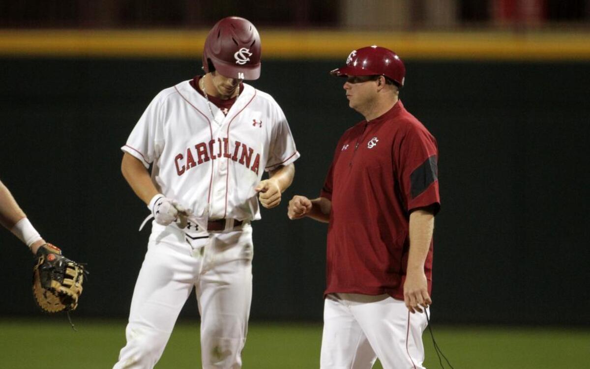 South Carolina's Madison Stokes gets instructions from first base coach and former Gamecock pitcher Blake Cooper