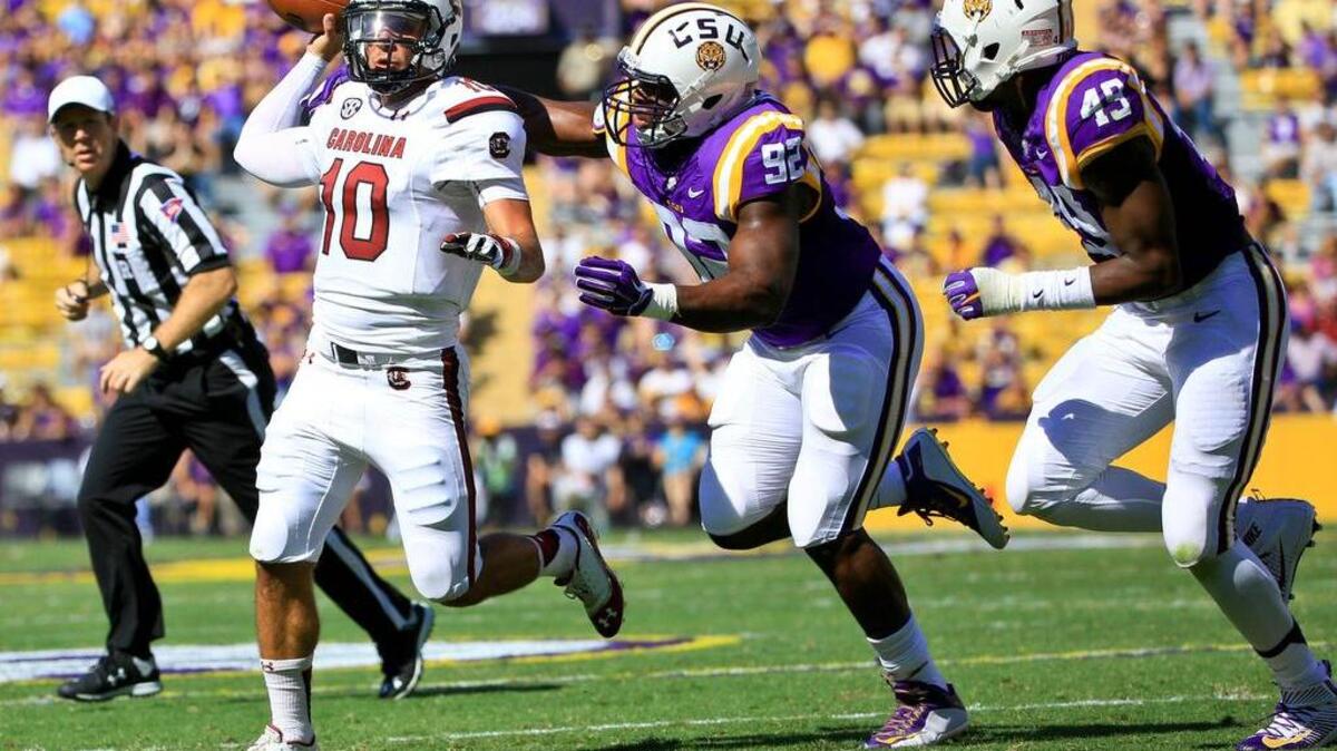 
South Carolina Gamecocks quarterback Perry Orth (10) is pressured by LSU Tigers defensive end Lewis Neal (92) during the first quarter of a game at Tiger Stadium. 
