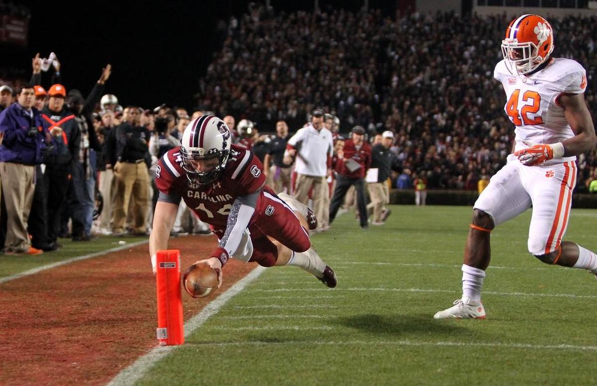South Carolina Gamecocks quarterback Connor Shaw (14) dives for a touchdown on a keeper in the first quarter as Clemson Tigers linebacker Stephone Anthony (42) chases during their game at Williams-Brice Stadium in Columbia, SC, Saturday, November 30, 2013.