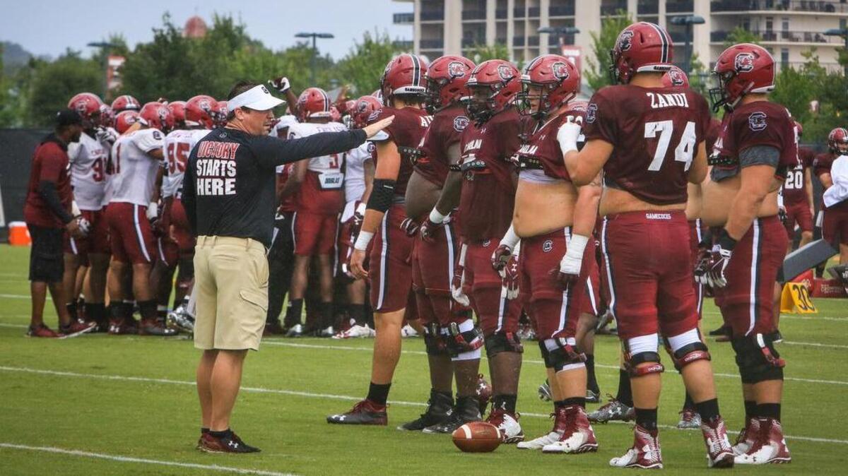 South Carolina head coach Will Muschamp gets the first team offensive line ready for a drill during a summer practice.