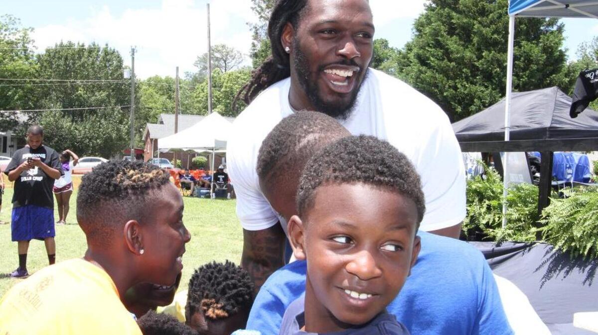 Fomer South Pointe High School football standout and NFL star Jadeveon Clowney huddles with a group of boys he coached at the Sylvia Circle Demons Skills Camp.